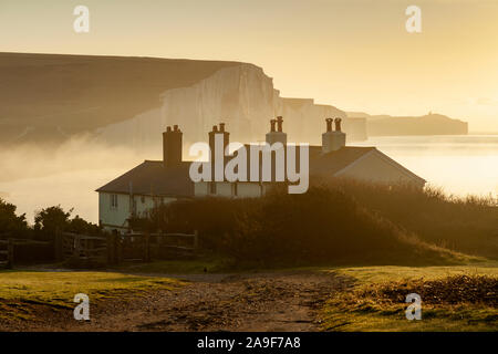 Inverno a sunrise Coastguard Cottages in East Sussex, Inghilterra. Sette sorelle scogliere in background. Foto Stock