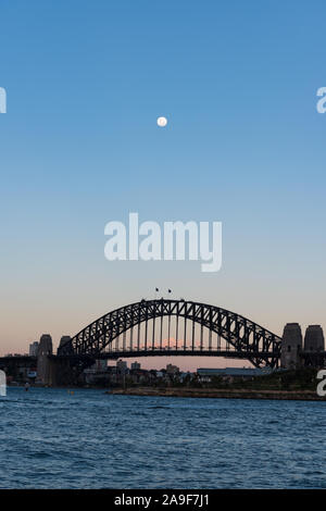 Sydney Harbour Bridge sul tramonto con la luna piena sul cielo chiaro Foto Stock