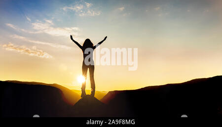 Donna di fronte al tramonto in montagna Foto Stock