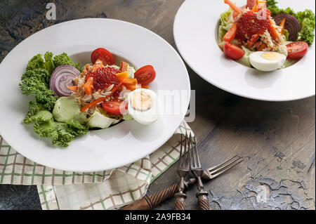 Due piastre con insalata di carne di granchio, avocado, verdure fresche e rosso salmone caviale. Servire su un tovagliolo a scacchi. Inquadratura orizzontale Foto Stock