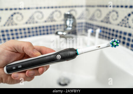 Elettrico spazzolino ricaricabile con un manico nero e cinque testine dello spazzolino da denti.fondo azzurro. Foto Stock