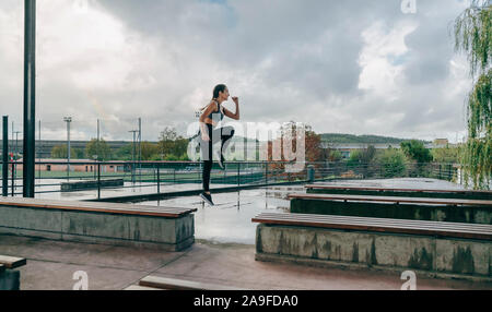 Ragazza saltando sulle panchine facendo formazione Foto Stock