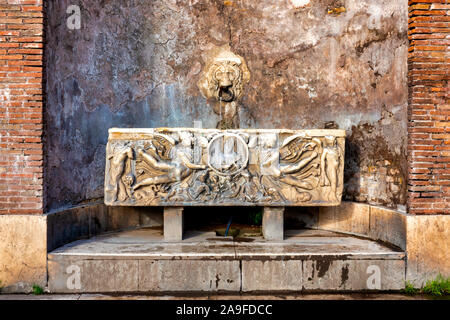 Fontana composta da una testa di leone e un antico sarcofago romano in Piazza del Colosseo, Roma Italia Foto Stock