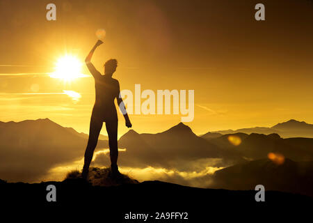 Donna in posa di vittoria di sunrise su un picco di montagna Foto Stock