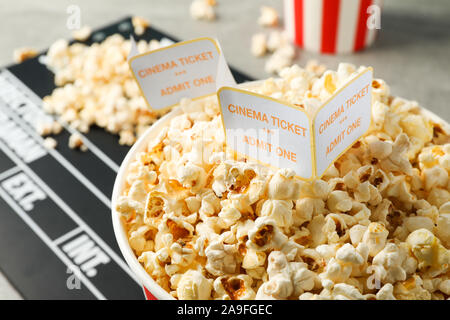 Clapperboard, biglietti e benne con popcorn su sfondo grigio, vista dall'alto Foto Stock