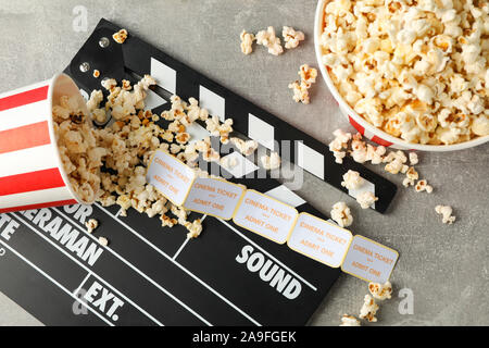 Clapperboard, biglietti e benne con popcorn su sfondo grigio, vista dall'alto Foto Stock