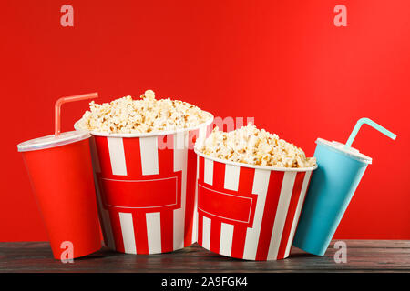 Il Popcorn tazze e bicchieri di carta contro lo sfondo di colore rosso, lo spazio per il testo Foto Stock