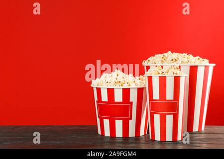 Le benne a strisce con popcorn contro lo sfondo di colore rosso, lo spazio per il testo Foto Stock