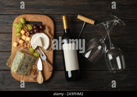 Bottiglia di vino, bicchieri, formaggi e frutta su sfondo di legno, vista dall'alto Foto Stock