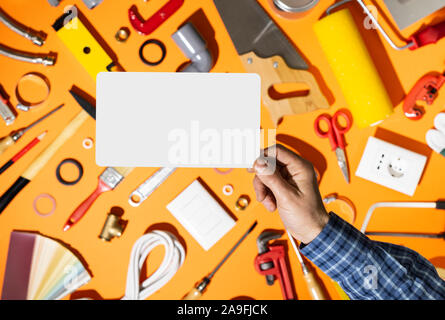 Professional repairman tenendo una scheda vuota e gli strumenti hardware in background, FAI DA TE e home concetto di rinnovamento Foto Stock