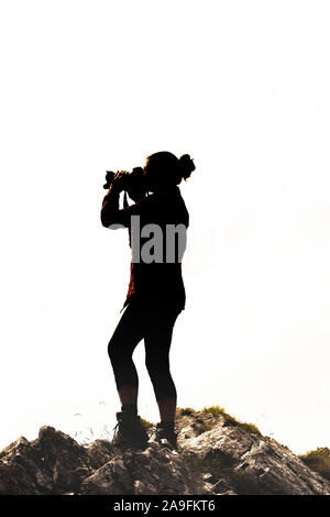 Silhouette di un fotografo di fronte a uno sfondo bianco Foto Stock