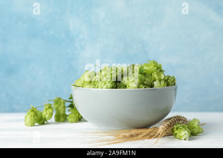 Ciotola con hop e spikelets bianco sul tavolo di legno, lo spazio per il testo Foto Stock