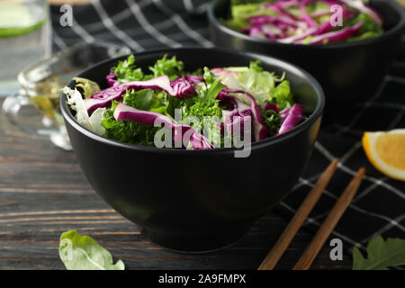 Bocce nero con insalata, bacchette e asciugamani su sfondo di legno, close up Foto Stock