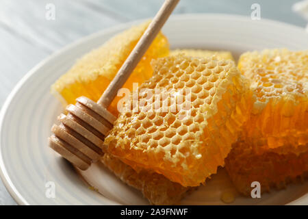 Piastra con bilanciere e favi su sfondo di legno, close up Foto Stock