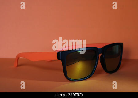 Occhiali da sole arancione su uno sfondo arancione. Accessori per proteggere dal sole. Foto Stock