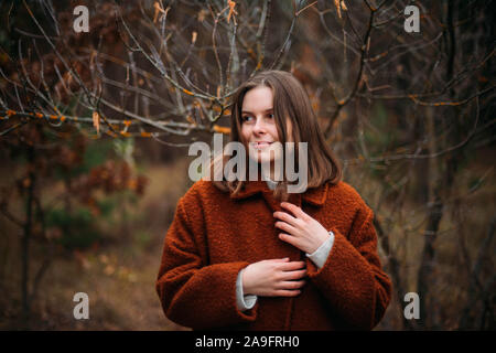 Close-up ritratto della bella giovane donna in piedi nel parco con alberi di caduta Foto Stock