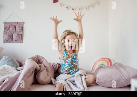 Ragazza giovane stretching e sbadigli al mattino nel suo letto a casa Foto Stock