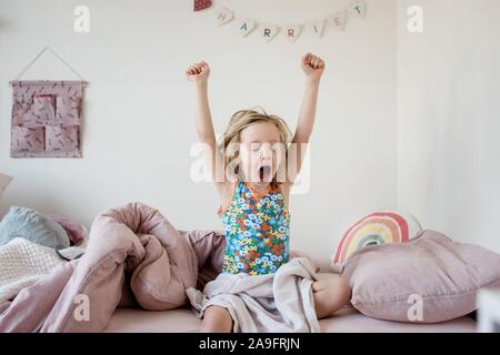 Ragazza giovane risveglio stretching al mattino nella sua camera da letto a casa Foto Stock