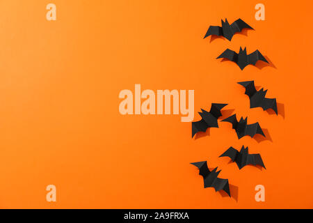 Pipistrelli decorativi su sfondo arancione, spazio per il testo Foto Stock