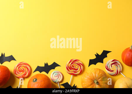 Candy, decorativi pipistrelli e zucche su sfondo giallo, vista dall'alto Foto Stock