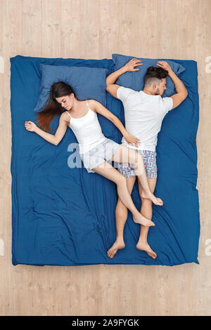 Andare a dormire. Coppia giovane che dorme sul letto vista superiore donna mettendo le gambe sull'uomo Foto Stock
