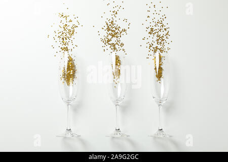 Bicchieri di champagne con glitter su sfondo bianco, spazio per il testo Foto Stock