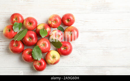 Composizione con mele rosse su bianco sullo sfondo di legno, lo spazio per il testo Foto Stock