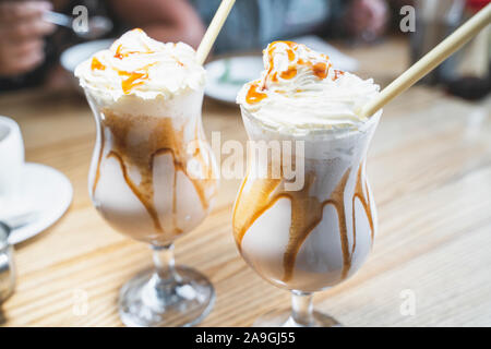 Milk Shake con panna montata e Topping Caramel in bicchieri con eco-friendly di bambù in paglia cafe. Libero di plastica e rifiuti zero concept Foto Stock