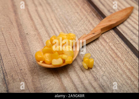 Dolci chicchi di mais in un cucchiaio di legno su una tavola di legno. Dieta Fitness. Dieta sana. Per una dolcezza. Close up Foto Stock