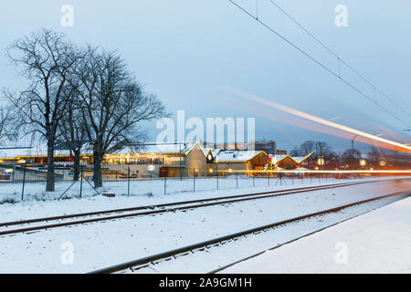 TALLINN, Estonia - 23 dicembre 2018: Le rotaie e le strisce di luce di passaggio di treni su nevoso inverno sera a Tallinn in Estonia su dicembre 23, 2018 Foto Stock