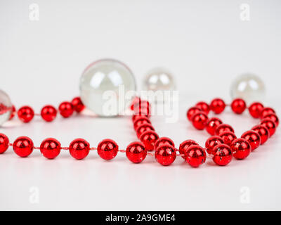 Perline rosso sfera trasparente giacciono su uno sfondo bianco. Foto Stock