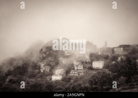 Immagine seppia dell'antico villaggio di montagna di Speloncato è avvolta nella nebbia nella nella regione della Balagne in Corsica Foto Stock