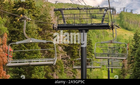 Telaio Panorama seggiovie contro verde vivace alberi e cielo nuvoloso a Park City in bassa stagione Foto Stock