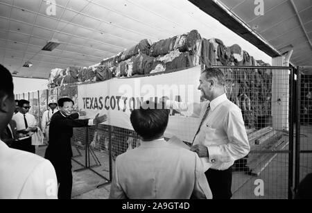 Stati Uniti Vice presidente Lyndon Johnson visita mulino tessile con uomini vietnamita in piedi di fronte ad una grande quantità di prodotti tessili con un 'Texas cotone U.S.A.' Banner, a Saigon, Vietnam del Sud, foto di Thomas J. O'Halloran, Maggio 1961 Foto Stock