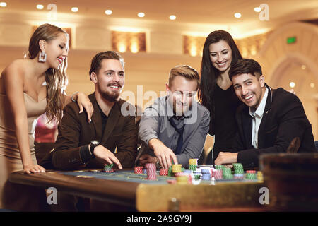 Allegro gruppo di amici gode di vincere alla roulette poker in un casinò. Foto Stock