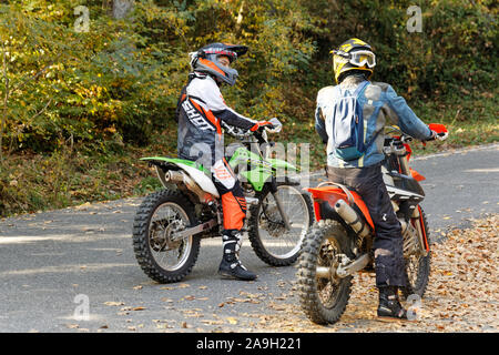 Due piloti di Motocross in piedi sulle loro moto e di parlarsi durante l'attesa per l'azienda. Foto Stock