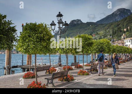 I turisti passeggiare lungo la passeggiata lungo il lago del grazioso borgo di Gargnano sul Lago di Garda, Italia Foto Stock