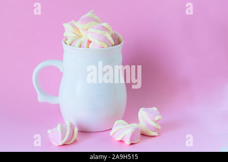 White tazza di cioccolato con rosa marshmallows su uno sfondo di colore rosa. Copia dello spazio. Foto Stock