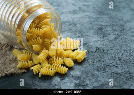 Pasta cruda in un vasetto di vetro su uno sfondo nero. Copia dello spazio. Foto Stock