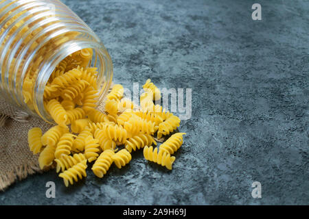 Pasta cruda in un vasetto di vetro su uno sfondo nero. Copia dello spazio. Foto Stock