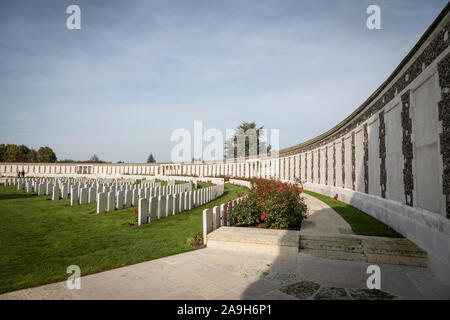 Alcuni perfettamente mantenuto graves allineare con il Memorial Wall (di soldati con noto alcun grave),a Tyne Cot cimitero militare, Belgio. Foto Stock