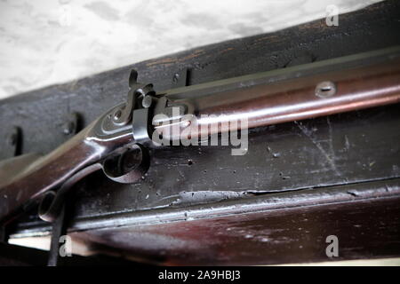 Close up dettaglio della vecchia flintlock fucile o moschetto, appeso a un vecchio fascio di quercia Foto Stock