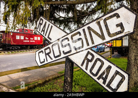 Red Caboose Motel Rail Crossing Sign Ronks Pennsylvania // RONKS, Pennsylvania - The Red Caboose Motel, vicino a Lancastter, Pennsylvania, è un motel e ristorante a tema ferroviario. Non è lontano da altre attrazioni a tema ferroviario e musei nelle vicinanze. Le sistemazioni dell'hotel sono in vecchie carrozze ferroviarie convertite. Foto Stock