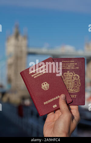 Mano che tiene il passaporto britannico insieme con altri passaporto UE contro il simbolo di Londra. Il viaggio dopo Brexit. Foto Stock