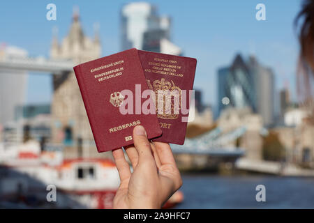 Mano che tiene il passaporto britannico insieme con altri passaporto UE contro il simbolo di Londra. Il viaggio dopo Brexit. Foto Stock