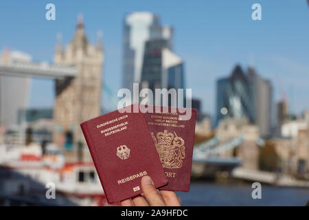 Mano che tiene il passaporto britannico insieme con altri passaporto UE contro il simbolo di Londra. Il viaggio dopo Brexit. Foto Stock