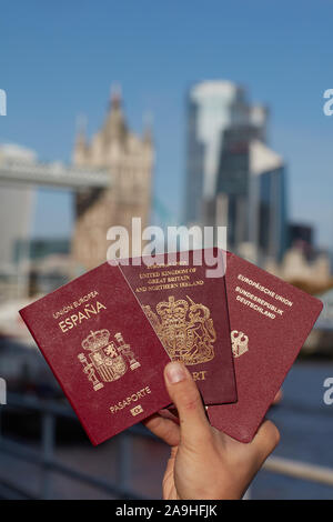 Mano che tiene il passaporto britannico insieme con altri passaporto UE contro il simbolo di Londra. Il viaggio dopo Brexit. Foto Stock