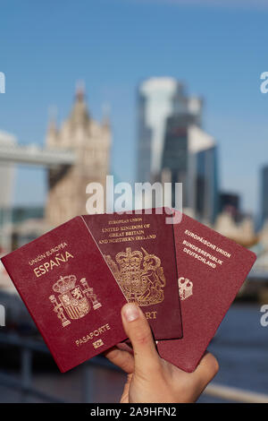 Mano che tiene il passaporto britannico insieme con altri passaporto UE contro il simbolo di Londra. Il viaggio dopo Brexit. Foto Stock