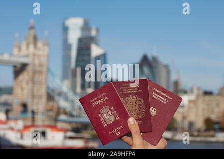 Mano che tiene il passaporto britannico insieme con altri passaporto UE contro il simbolo di Londra. Il viaggio dopo Brexit. Foto Stock