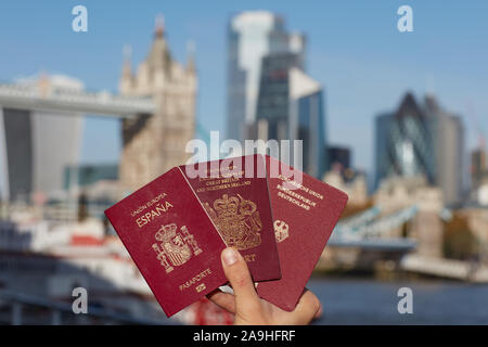 Mano che tiene il passaporto britannico insieme con altri passaporto UE contro il simbolo di Londra. Il viaggio dopo Brexit. Foto Stock